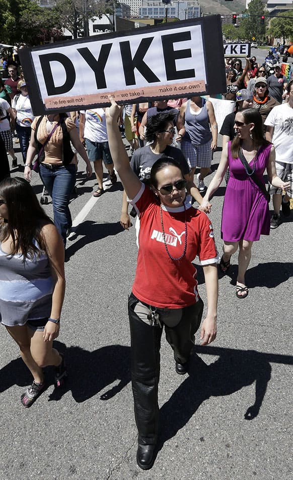 Tina Burton, of Salt lake City, carries a sign during the Dyke Rally and March before the opening ceremonies of the Utah Pride Festival, in Salt Lake City.
