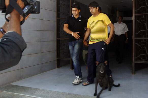 A Mumbai Crime Branch official, left in black, escorts bookie Ashwin Agarwal to the Esplande court for spot fixing in cricket, in Mumbai.