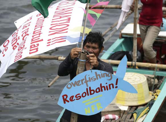 A Filipino fisherman hangs a message upon docking his outrigger to join a rally near the Philippine Senate following a fluvial protest to mark National Fisherfolk Day, in Manila.