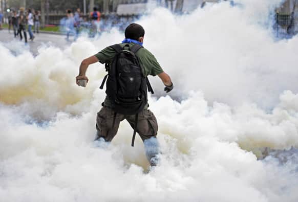 A man runs as riot police use tear gas and pressurized water to quash a peaceful demonstration by hundreds of people staging a sit-in protest to try and prevent the demolition of trees at an Istanbul park.