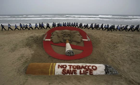 Students perform next to a sand sculpture created by sand artist Sudarshan Pattnaik during an awareness campaign on the eve of World No Tobacco Day, at the Bay of Bengal coast in Puri, Orissa.