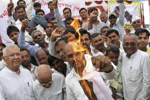 Farmers burn a copy of Gujarat state government`s notification for acquiring their farm land for development purposes during a protest in Vitthalapur village, 75 kilometers (47 miles) north of Ahmedabad.