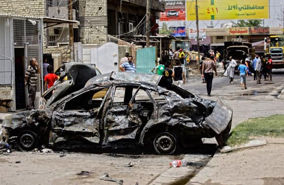 Civilians inspect the site of a parked car bomb attack near a popular restaurant in the Ur neighborhood in northern Baghdad, Iraq.