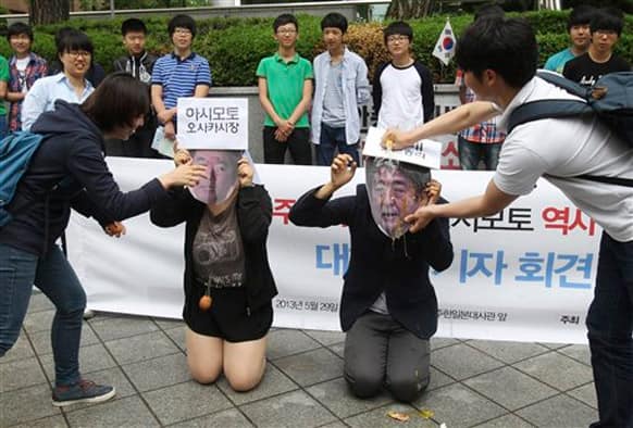 South Korean college students crack eggs on masks of Japanese Prime Minister Shinzo Abe and Japan`s Osaka Mayor Toru Hashimoto, left, during a rally against Japan in front of the Japanese embassy in Seoul, South Korea.