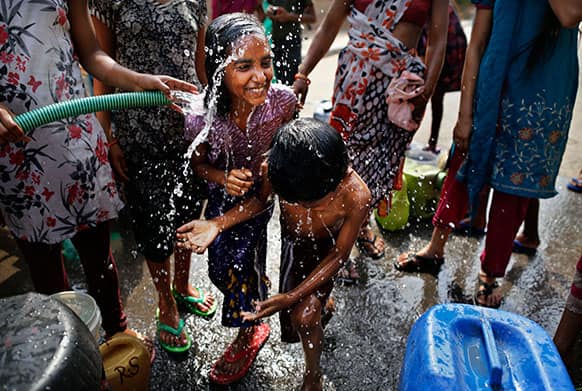 Indian children react, as they are sprayed with water being distributed by the municipality in a local slum on a hot summer day in New Delhi.