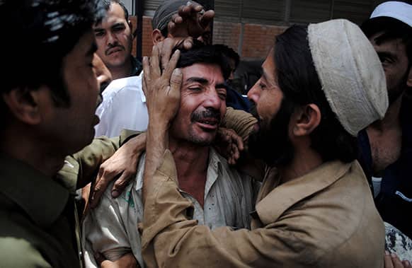 People comfort a family member of a female polio worker who was killed by unknown gunmen, at a local hospital in Peshawar, Pakistan.