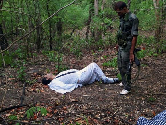 An Indian security person stands near the body of one of the victims of Saturday’s Maoist attack in a densely forested area in Bastar, about 345 kilometers (215 miles) south of Raipur, Chhattisgarh.
