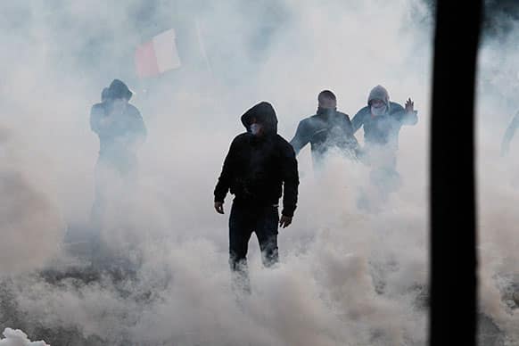 Anti-gay marriage demonstrators face riot police, not seen, while teargas canisters smoke during clashes in Paris, France.