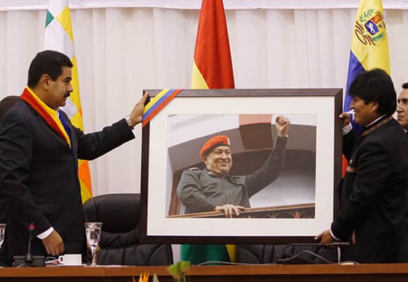 Venezuela`s President Nicolas Maduro, left, gives a photograph of late President Hugo Chavez to Bolivia`s President Evo Morales at a meeting in Cochabamba, Bolivia.