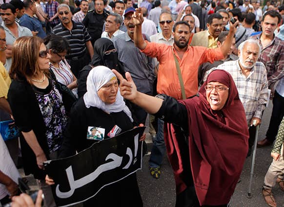 Egyptian opposition activists shout anti-Muslim brotherhood slogans as anti-riot soldiers, not shown, prevent them from getting close to the Shura Council, the upper house of Parliament, during a protest against the new judicial law in Cairo, Egypt. Arabic reads,