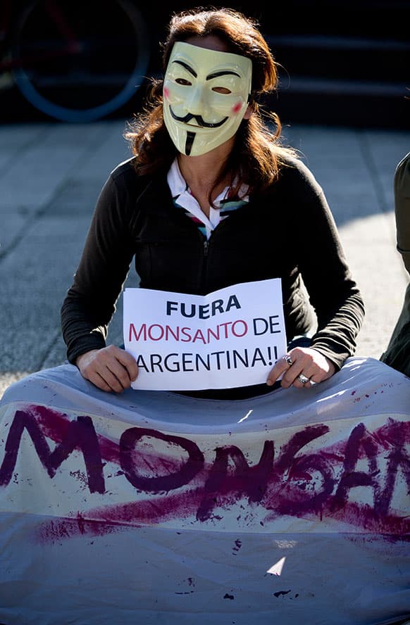 A demonstrator wearing as Guy Fawkes mask holds a sign that reads in Spanish