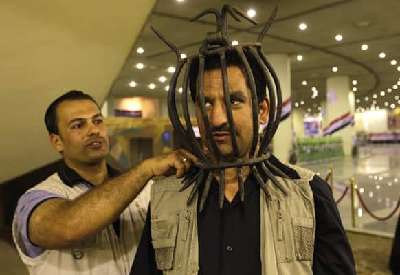 An Iraqi man wears a torture device used by the regime of Iraq`s ousted leader Saddam Hussein at the Shaheed Monument in Baghdad.