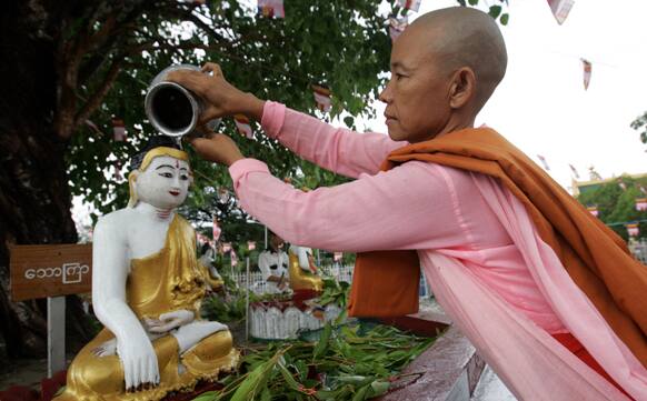 A Buddhist nun pours waterover a statue of Buddha under a Bayan tree during the Full Moon day of Kasone, known as Buddha`s Birthday, at a pagoda in Yangon, Myanmar.