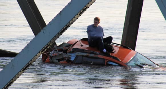This photo provided by Francisco Rodriguez, a man is seen sitting atop a car that fell into the Skagit River after the collapse of the Interstate 5 bridge, in Mount Vernon, Wash.