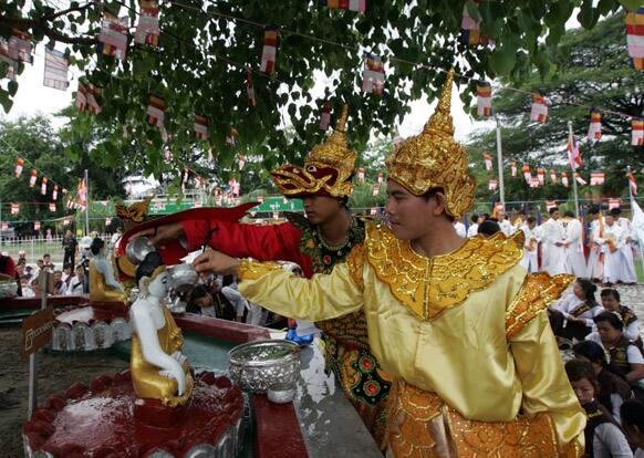 Wearing special costumes, Buddhist devotees pour water over a Buddha`s statue under a Banyan tree during the Full Moon day of Kasone, known as Buddha`s Birthday, at a pagoda in Yangon, Myanmar.