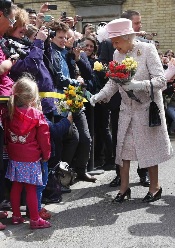 Britain`s Queen Elizabeth II receives bouquets of flowers from children as she is welcomed during a visit to Cambridge, England.