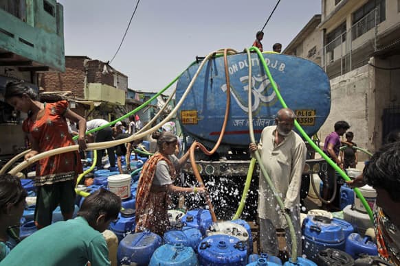 People fill water, supplied by a government tanker, into barrels in New Delhi. Many areas of the Indian capital are facing acute water shortage, a repeated annual phenomenon during summer when taps go dry as demand rises.