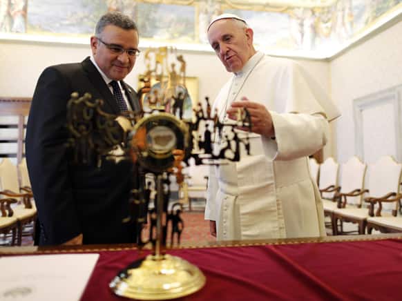 Pope Francis speaks with El Salvador`s President Mauricio Funes as they stand in front of a reliquary containing a fragment of the vestment that archbishop Oscar Romero was wearing when he was assassinated, during a private audience at the Vatican.