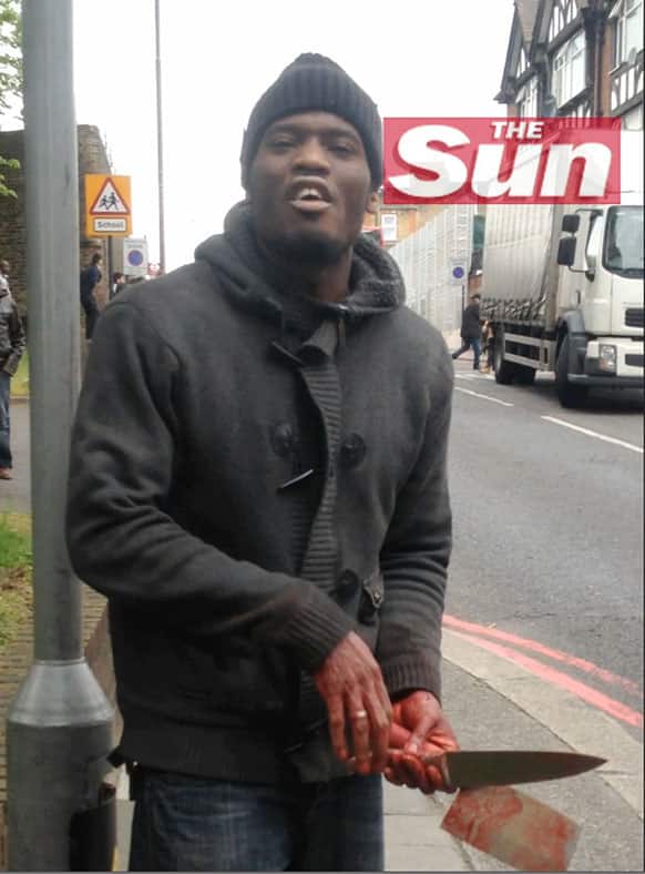 This image taken from video made available by The Sun newspaper shows what appears to be one of the attackers speaking to the camera, holding a knife and a cleaver in his bloodied hands, after a brutal attack in broad daylight Wednesday, May 22, 2013 near a military barracks in London.