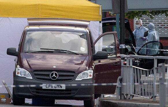British forensic officers attend the scene of an apparent attack which has left one man confirmed dead and two people wounded near Woolwich barracks in London.