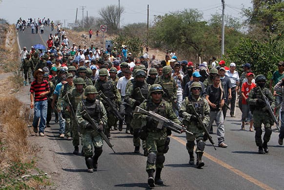 Soldiers are escorted by residents and armed members of a local self-defense group into the town of Buenavista as a show of good faith while both sides negotiate the release of four self-defense group members who were arrested by authorities earlier in the day, in Buenavista, Mexico.