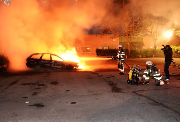 Firemen extinguish a burning car in the Stockholm suburb of Kista after youths rioted in several different suburbs around Stockholm for a third executive night.