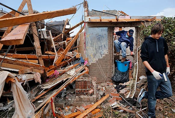 Jimmy Carter climbs through a window in the front of his home as Carter, his wife, and friends spent the morning looking for salvageable items from their home in Moore, Okla.