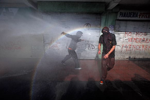 Drenched protestors run from a water cannon near the Chilean Congress where President Sebastian Pinera delivered his final state of the nation address, in Valparaiso, Chile.