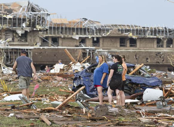 People go through the debris near Telephone Road and SW 4th Street after a tornado moves through Moore, Okla.