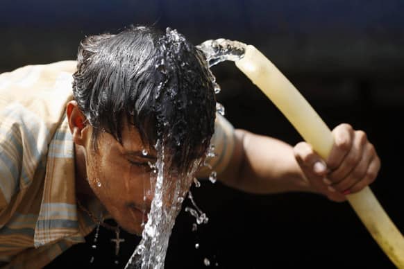 An Indian commuter splashes water from a pipe onto his face to get respite from the heat at the railway station in Allahabad.