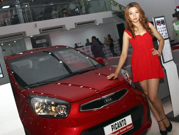 A Myanmar model poses next to a Kia Picanto during the opening ceremony of Kia Motors showroom in Yangon, Myanmar.
