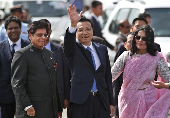 Chinese Premiere Li Keqiang waves as he is received by Indian Junior Minister for External Affairs, E. Ahamed, left, after he arrives in New Delhi.