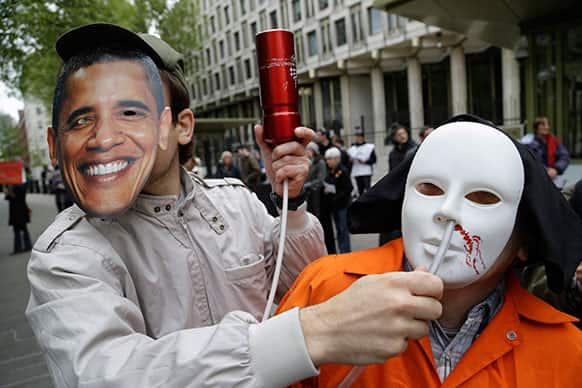 A protester, left, wearing a mask depicting US President Barack Obama, poses for the photographers as he pretends to force-feed another protester depicting a detainee of the US detention facility at Guantanamo Bay, Cuba, during a demonstration outside the US Embassy in central London.