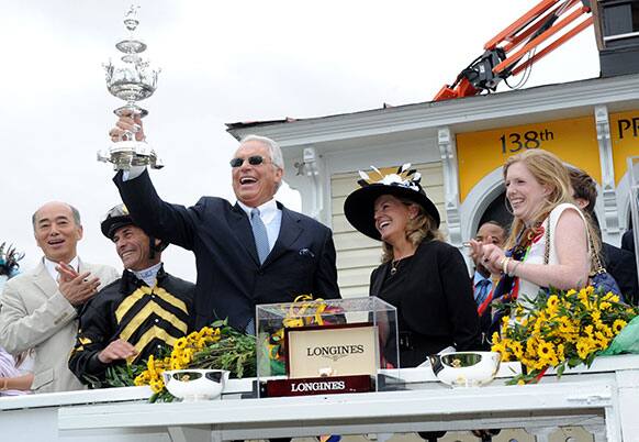 Trainer D. Wayne Lukas, with trophy, jockey Gary Stevens, second left, and Erin Kelley, right, daughter of owner Brad Kelley, celebrate after their horse Oxbow won the 138th Preakness Stakes, in Baltimore, MD.