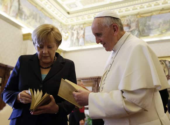 Pope Francis is presented with a gift by German Chancellor Angela Merkel during a private audience at the Vatican.