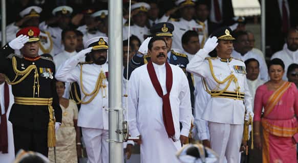 Sri Lankan President Mahinda Rajapaksa, sings the national anthem as, Army Commander Lt. Gen. Jagath Jayasuriya, Navy Commander Vice Admiral Jayanath Colombage and Air Force Commander Air Marshal Harsha Abeywickrama salute during a war victory parade in Colombo.
