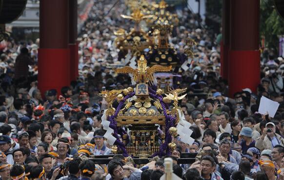 Festival goers carry portable shrines, marching through the court yard of Sensoji Temple during the annual Sanja Festival at Tokyo`s Asakusa district.