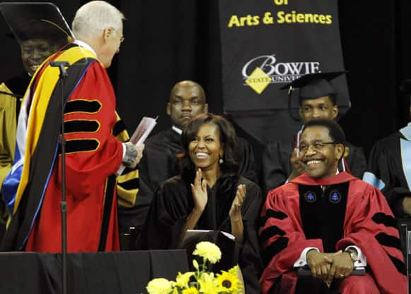 First lady Michelle Obama applauds Regent Barry P. Gossett, left, as she sits with Provost Dr. Weldon Jackson, right, during the commencement ceremony for Bowie State University.