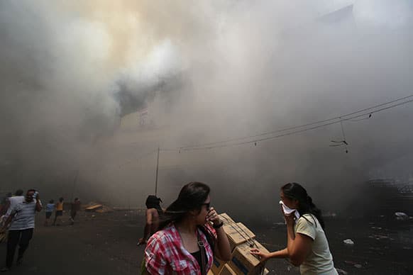 Filipino women cover their noses as they pass by a still burning mall in the shopping district of Divisoria in Manila, Philippines. Authorities are still determining the cause of the fire.