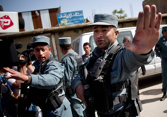 Afghan policemen stop people from approaching the scene where a suicide car bomber attacked a NATO convoy in Kabul, Afghanistan.