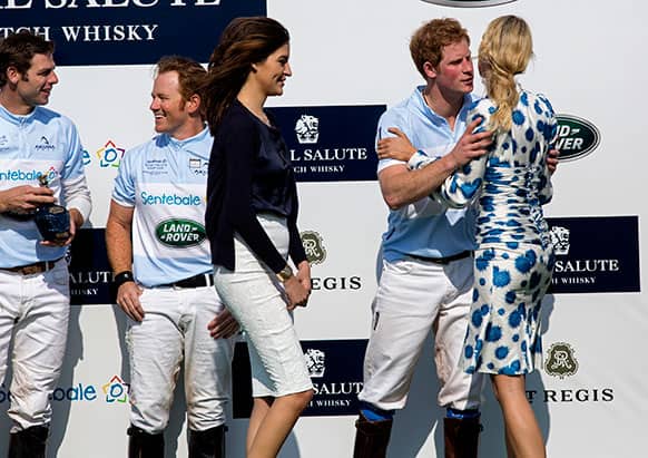 Britain`s Prince Harry embraces model Karolina Kurkova after the Sentebale Royal Salute Polo Cup charity match in Greenwich, Conn. Teammates Malcolm Borwick, far left, and Marc Ganzi join him on the podium after the Sentebale team won.
