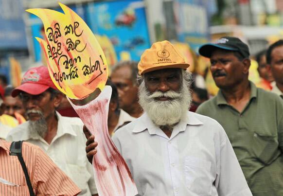 A Sri Lankan man carries a cut-out of a flame during a protest demanding the reduction of electricity rates during a protest in Colombo, Sri Lanka.