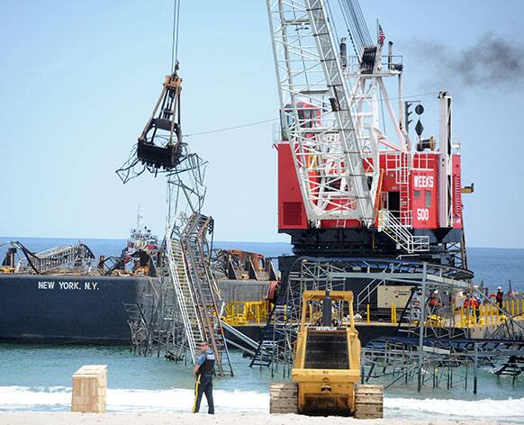 Contractors from Weeks Marine begin removing the Jet Star Roller Coaster from the Seaside Heights water more than six months after Superstorm Sandy dropped it there, and less than two weeks before Memorial Day.