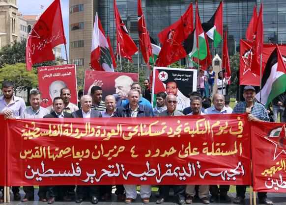 Palestinians from the Democratic Front for the Liberation of Palestine, carry flags and a banner during a sit-in marking the 65th anniversary of the