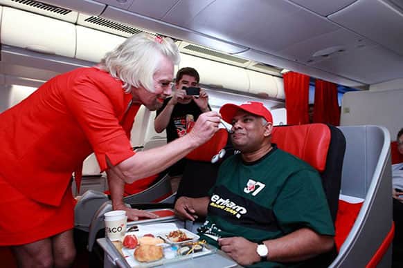 AirAsia chief Tony Fernandes, right, is served by British business magnate Richard Branson who is dressed as a female flight attendant, while flying from Perth, Australia to Kuala Lumpur, Malaysia.