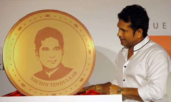 Sachin Tendulkar looks at a replica of a gold coin embossed with his face during its unveil on the occasion of “Akshay Tritiya” in Mumbai.