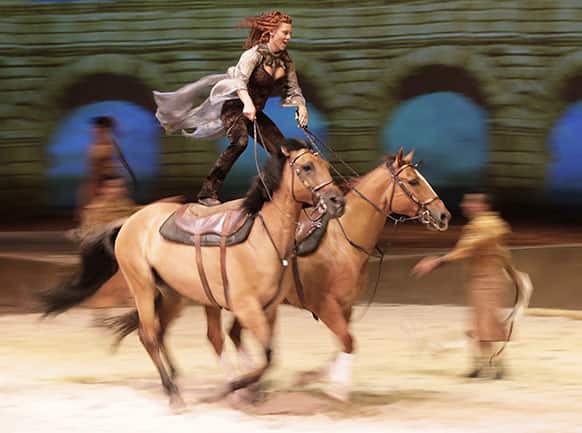 Fairland Ferguson rides while standing on the backs of a pair of horses during a dress rehearsal for the show