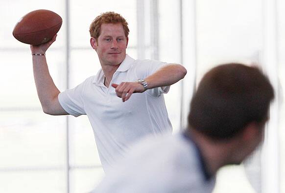 Britain`s Prince Harry tries his hand at throwing a football to a receiver, right, at the US Air Force Academy in Colorado Springs, Colo.