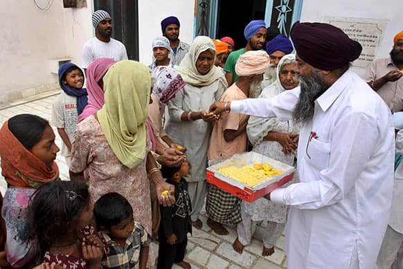 Residents of Jatti Umra, native village of Pakistan`s former prime minister Nawaz Sharif, distribute sweets as they celebrate Sharif’s election victory at Jatti Umra, near Amritsar, India.