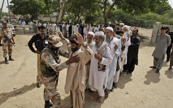 A Pakistani paramilitary soldier checks voters before they enter a polling station to cast their ballots, in Karachi, Pakistan.
